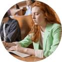A female student with red hair looks worryingly at her school work.