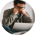 A man holds his head as he deals with stress looking at a laptop